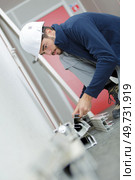 worker sorting through lengths of plastic on floor. Стоковое фото, агентство Ingram Publishing / Фотобанк Лори