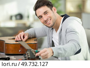 a happy man is fixing a guitar. Стоковое фото, агентство Ingram Publishing / Фотобанк Лори