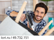 man using sealant gun to repair broken chair. Стоковое фото, агентство Ingram Publishing / Фотобанк Лори