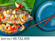 Tasty large grilled tilapia fish with fruit. Popular Malay or Indonesian food.. Roasted whole tilapia with citrus sauce. Стоковое фото, агентство Ingram Publishing / Фотобанк Лори