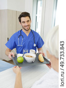 male nurse serving food to senior female patient in clinic. Стоковое фото, агентство Ingram Publishing / Фотобанк Лори