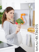 attractive pregnant woman holding broccoli and refusing anything else. Стоковое фото, агентство Ingram Publishing / Фотобанк Лори