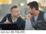 suited man and workman looking at laptop outdoors. Стоковое фото, агентство Ingram Publishing / Фотобанк Лори