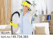 attractive tired woman hoovering sofa in using vacuum cleaner. Стоковое фото, агентство Ingram Publishing / Фотобанк Лори