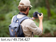 rear view of male backpacker using camera in rural setting. Стоковое фото, агентство Ingram Publishing / Фотобанк Лори