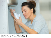 woman tightening pipe under sink with worktool at home. Стоковое фото, агентство Ingram Publishing / Фотобанк Лори