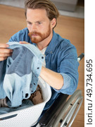 young man in wheel-chair doing laundry at home. Стоковое фото, агентство Ingram Publishing / Фотобанк Лори
