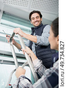 woman securing stepladder while man fixes window blind. Стоковое фото, агентство Ingram Publishing / Фотобанк Лори