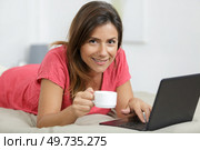 woman layed on bed drinking coffee while using laptop. Стоковое фото, агентство Ingram Publishing / Фотобанк Лори