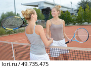 Identical twins shaking hands over tennis net. Стоковое фото, агентство Ingram Publishing / Фотобанк Лори