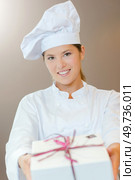 Chef holding forwards a gift wrapped box. Стоковое фото, агентство Ingram Publishing / Фотобанк Лори