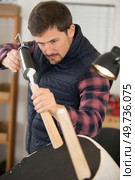 man using sealant gun to repair broken chair. Стоковое фото, агентство Ingram Publishing / Фотобанк Лори