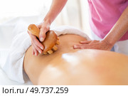 Crop anonymous therapist massaging with wooden therapy tool on back of anonymous client during physiotherapy session in osteopathy clinic. Crop masseur massaging back of client in physiotherapy clinic with wooden therapy tool. Стоковое фото, агентство Ingram Publishing / Фотобанк Лори