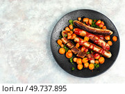 Grilled turkey sausages with roasted carrots on the plate. BBQ roast Bratwurst meat sausages. Copy space.. Grilled sausages served on a black plate. Стоковое фото, агентство Ingram Publishing / Фотобанк Лори