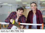 happy man is using a handsaw with colleague. Стоковое фото, агентство Ingram Publishing / Фотобанк Лори