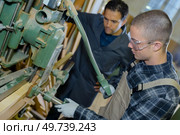 apprentice worker learning on factory machine. Стоковое фото, агентство Ingram Publishing / Фотобанк Лори