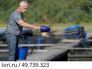a fish farmer throwing feeds. Стоковое фото, агентство Ingram Publishing / Фотобанк Лори