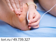 Woman's hand attaching a muscle stimulator electrode to the inner foot for therapeutic treatment. Стоковое фото, фотограф Татьяна Степанищева / Фотобанк Лори