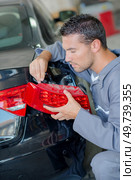 Mechanic with new light unit. Стоковое фото, агентство Ingram Publishing / Фотобанк Лори