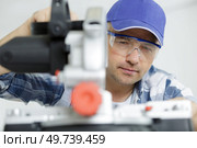 worker holds the miter saw and a piece of plywood. Стоковое фото, агентство Ingram Publishing / Фотобанк Лори