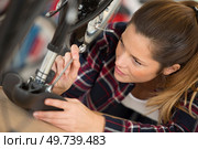 female bicycle mechanic is fixing a saddle. Стоковое фото, агентство Ingram Publishing / Фотобанк Лори
