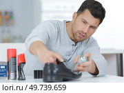 man holding spray in front of boots. Стоковое фото, агентство Ingram Publishing / Фотобанк Лори