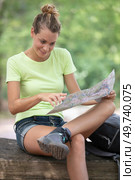 female hiker sat on tree-trunk looking at map. Стоковое фото, агентство Ingram Publishing / Фотобанк Лори