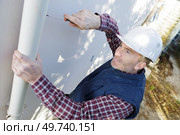 workman replacing guttering on exterior of house. Стоковое фото, агентство Ingram Publishing / Фотобанк Лори