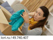 woman unimpressed with clothes received by mail order. Стоковое фото, агентство Ingram Publishing / Фотобанк Лори