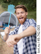 young man holding a fly swatter outdoors. Стоковое фото, агентство Ingram Publishing / Фотобанк Лори