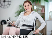 young woman in a wheelchair holding a magazine. Стоковое фото, агентство Ingram Publishing / Фотобанк Лори