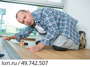 handyman installing wooden floor in new house. Стоковое фото, агентство Ingram Publishing / Фотобанк Лори
