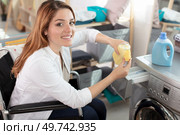 young disabled woman on wheelchair using washing machine. Стоковое фото, агентство Ingram Publishing / Фотобанк Лори