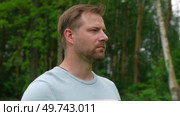 Handsome young man standing outdoors. Male thinking looking around feel happy, calm and serious. Green park background. Guy business employer, businessman manager inspired in nature. Diversity People. Стоковое видео, видеограф Марина Демидюк / Фотобанк Лори