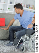 handicapped man trying to sit in a sofa. Стоковое фото, агентство Ingram Publishing / Фотобанк Лори