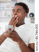 young man yawning while sitting on the sofa. Стоковое фото, агентство Ingram Publishing / Фотобанк Лори