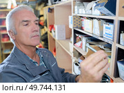 mature craftsman picking something on shelve in his workshop. Стоковое фото, агентство Ingram Publishing / Фотобанк Лори