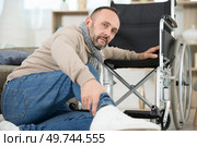 paralysed man sat on the floor beside his wheelchair. Стоковое фото, агентство Ingram Publishing / Фотобанк Лори