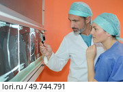 Doctor looking at xray with magnifying glass. Стоковое фото, агентство Ingram Publishing / Фотобанк Лори