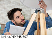 man changing light bulb in pendant lamp indoors. Стоковое фото, агентство Ingram Publishing / Фотобанк Лори