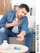 young man with asthma attack reaching for inhaler from table. Стоковое фото, агентство Ingram Publishing / Фотобанк Лори