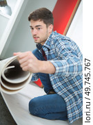 a contractor is unrolling underlay. Стоковое фото, агентство Ingram Publishing / Фотобанк Лори