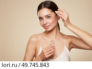 Young beautiful woman applying face serum with pipette. Cosmetic procedures for facial skin care. Стоковое фото, агентство Ingram Publishing / Фотобанк Лори