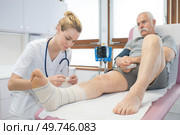 doctor bandaging seniors patients leg in hospital. Стоковое фото, агентство Ingram Publishing / Фотобанк Лори