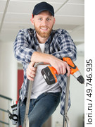 happy male builder standing on ladder with drill. Стоковое фото, агентство Ingram Publishing / Фотобанк Лори