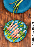 Plate with bacon wrapped asparagus on rustic table. Top view, flat lay. Green asparagus prosciutto ham wraps. Стоковое фото, агентство Ingram Publishing / Фотобанк Лори
