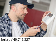concentrated man screwing a device on the wall. Стоковое фото, агентство Ingram Publishing / Фотобанк Лори