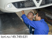 mechanic and male trainee working underneath car together. Стоковое фото, агентство Ingram Publishing / Фотобанк Лори