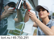 happy woman cleaning window with rag and cleanser spray. Стоковое фото, агентство Ingram Publishing / Фотобанк Лори