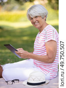 smiling senior woman using digital tablet at the park. Стоковое фото, агентство Ingram Publishing / Фотобанк Лори